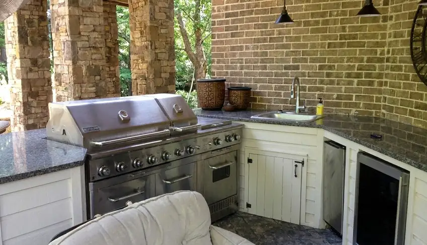Covered outdoor kitchen with stainless grill, granite counters and sink in Atlanta GA