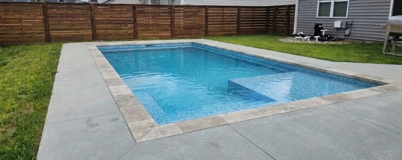 Rectangular inground pool with travertine coping and tanning ledge in Atlanta GA